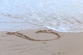 Heart drawn on sand with waves crashing, beach background, top v Royalty Free Stock Photo